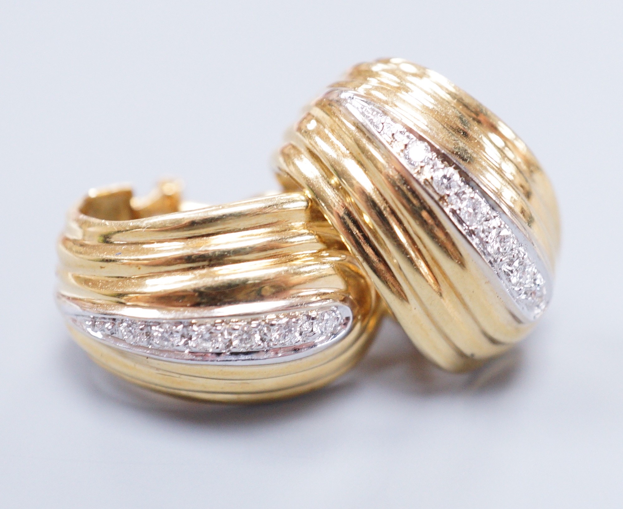 A pair of 18k yellow metal and diamond chip scroll shaped ear-clips, 2cm, gross 13 grams